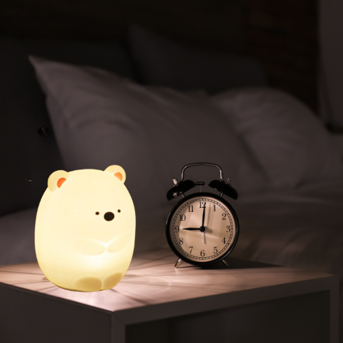 ours veilleuse posé sur une table de chevet dans une chambre sombre