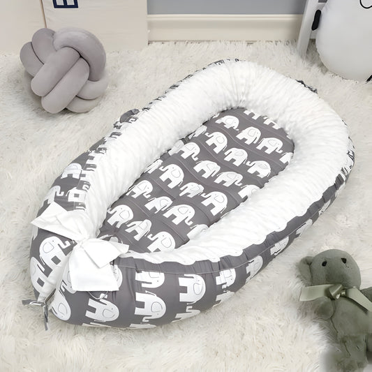 réducteur de lit bébé éléphant posé sur un tapis