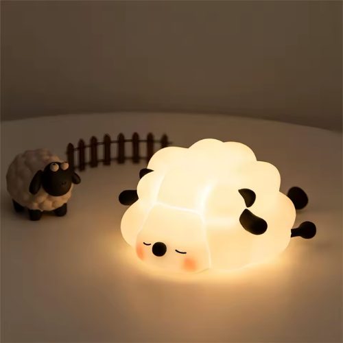 petite veilleuse bebe mouton qui éclaire sur une table blanche