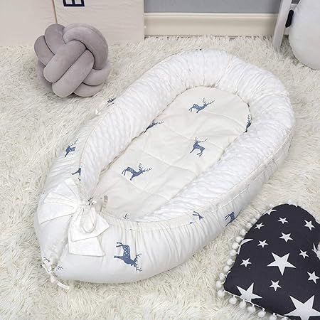 réducteur de lit bebe posé sur un tapis blanc