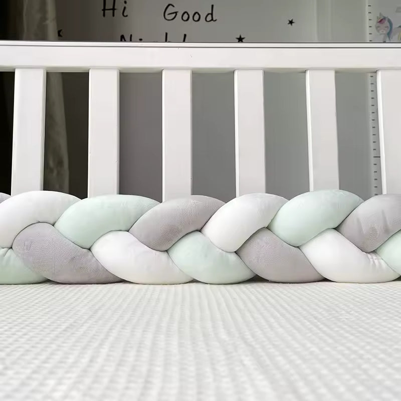tour de lit bebe tresse grise et verte dans un lit a barreaux