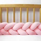 tresse de lit bébé rose devant des barreaux de lit