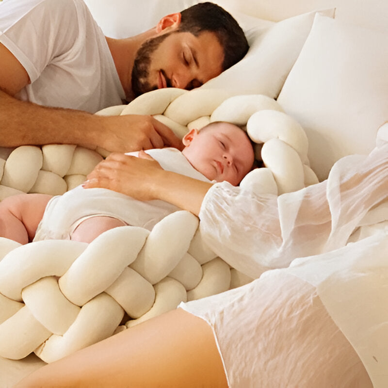 bébé qui dort entouré de sa tresse de lit beige