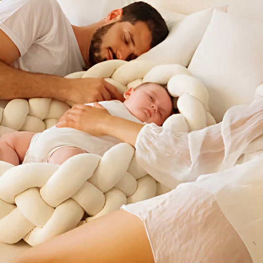 bébé qui dort entouré de sa tresse de lit beige